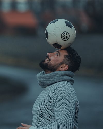 Playful man skillfully balancing a ball on his head, showcasing coordination and enjoyment in a lighthearted moment.